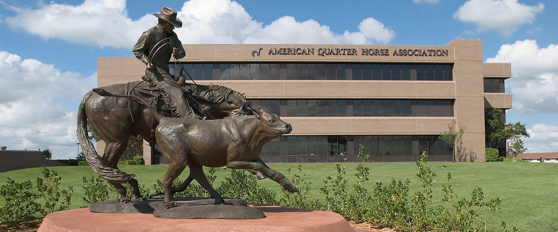 Statue of man on horse lassoing a cow